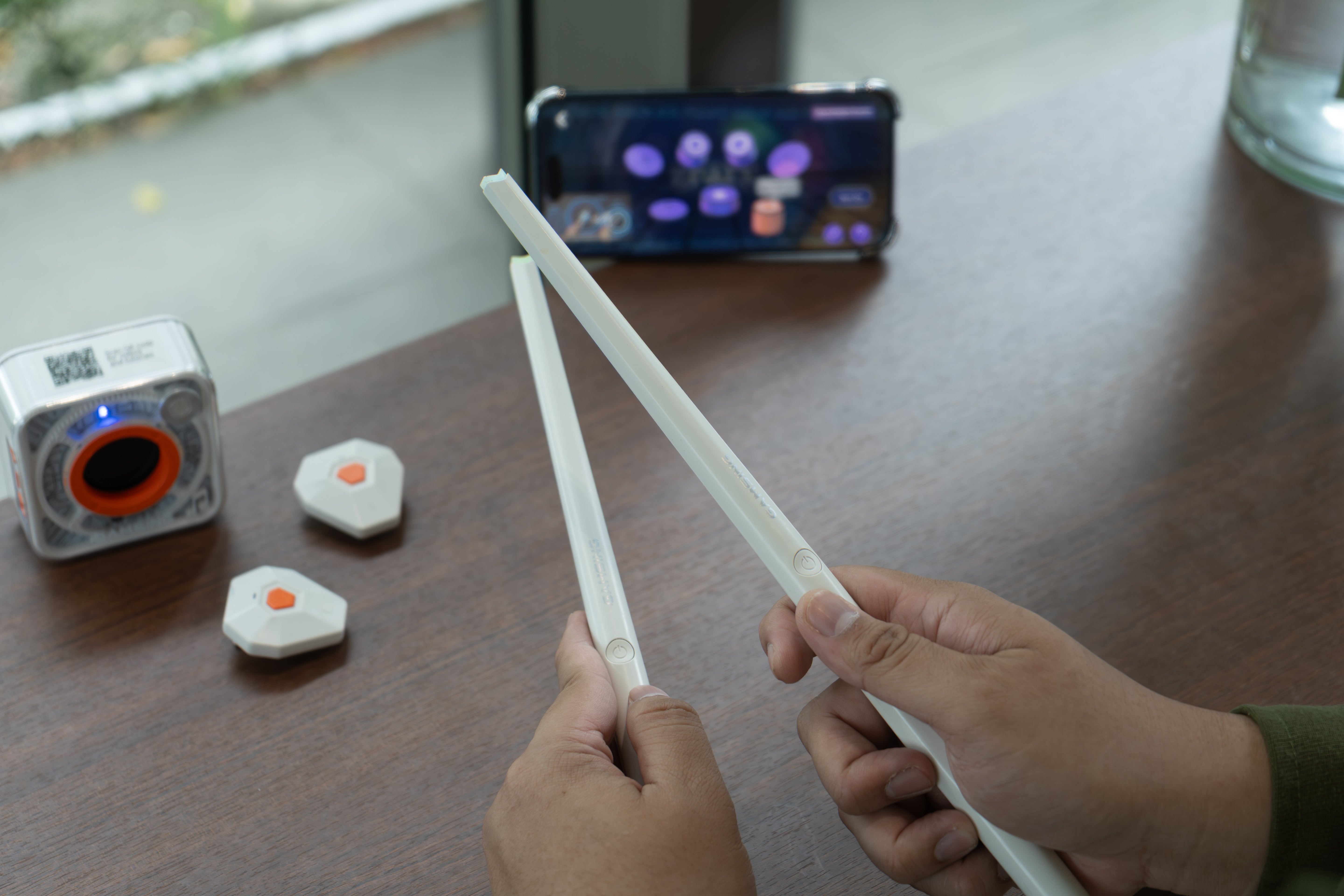 beginner practicing playing drums along with songs using air drum sticks and a mobile app on a table